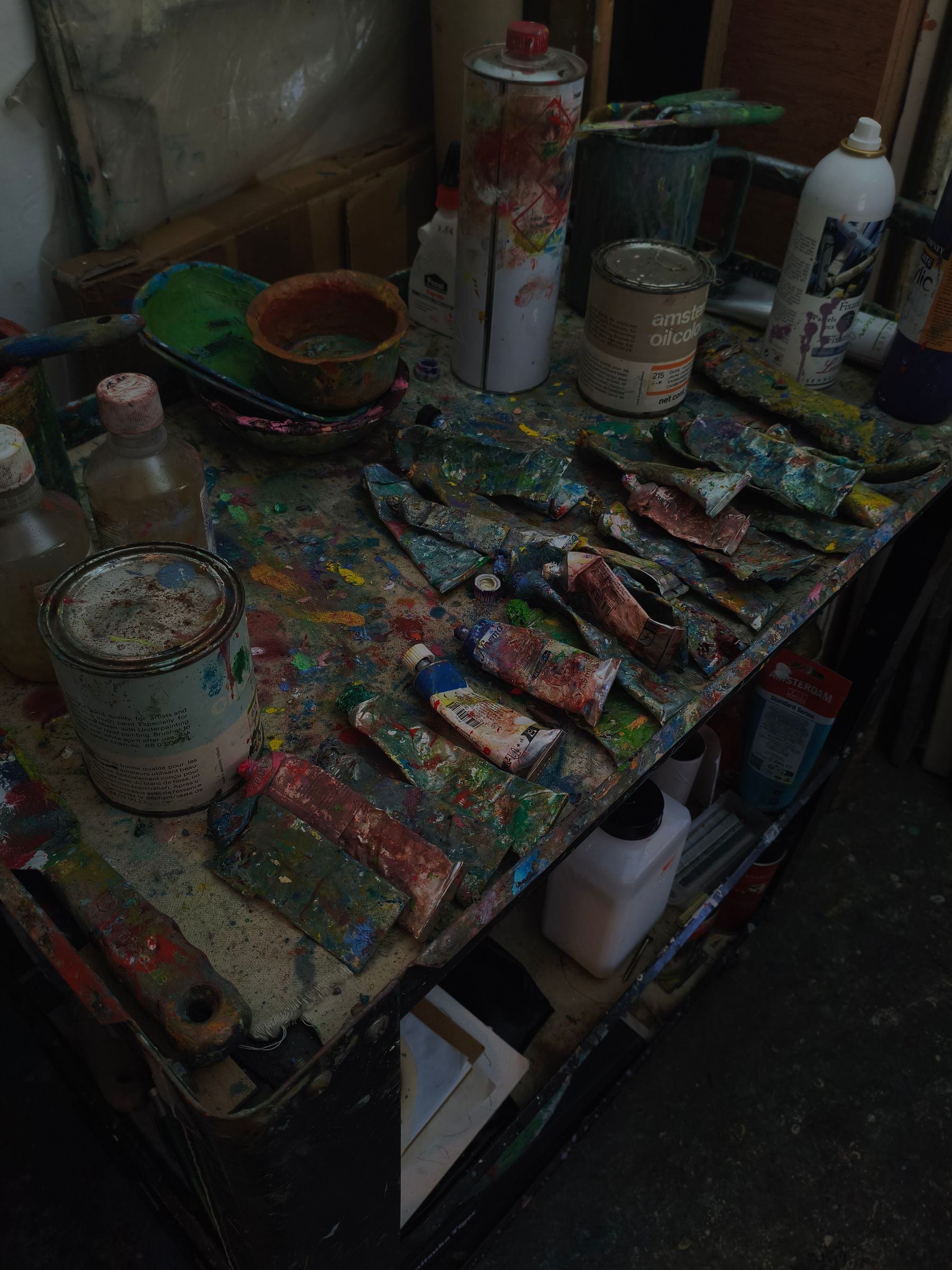 Latas, potes de tinta e paletas coloridas sobre uma mesa de trabalho.